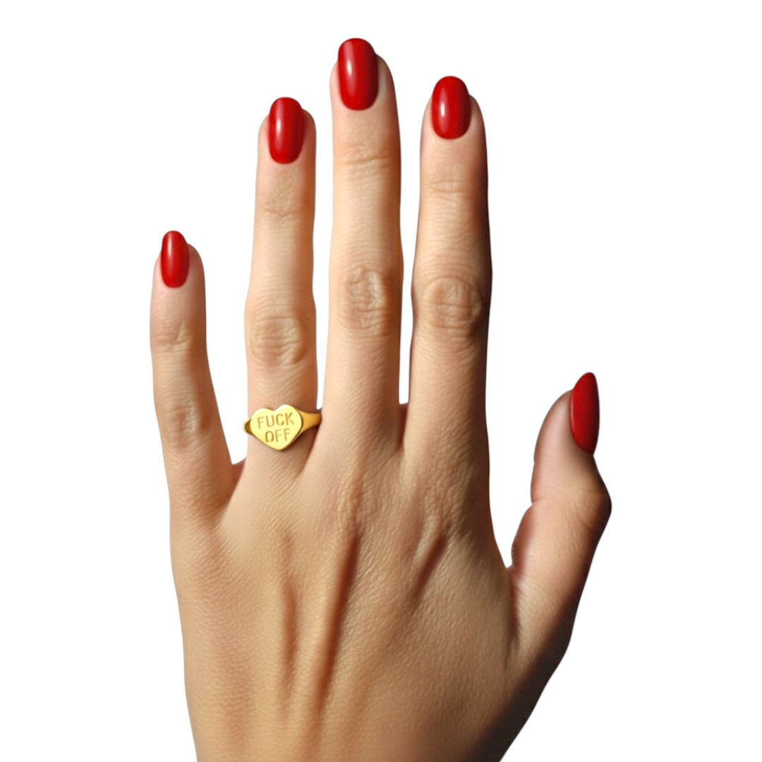 Hand with red nail polish wearing a gold fuck off ring on a white background