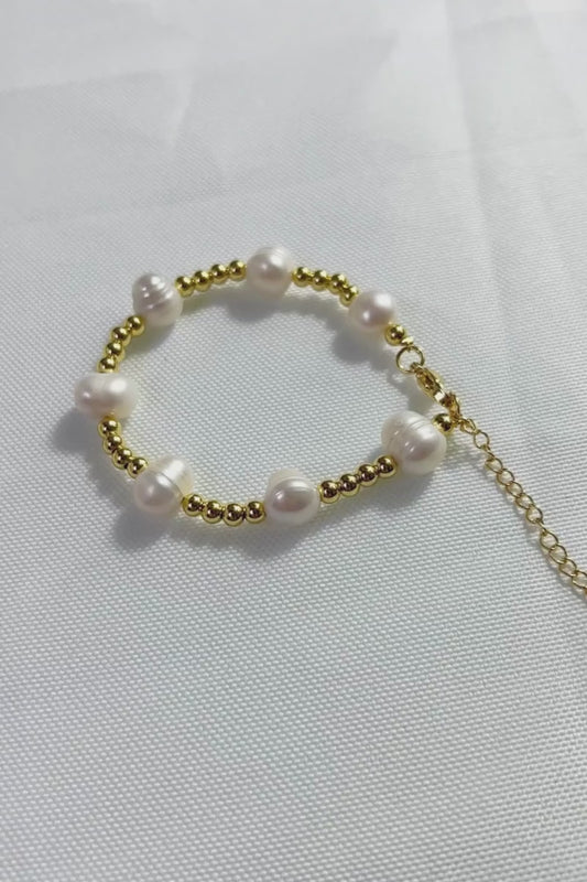 Elegante pulsera de perlas blancas y doradas